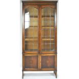 An oak bookcase with two lead glazed doors enclosing three adjustable shelves