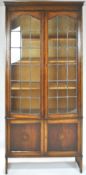 An oak bookcase with two lead glazed doors enclosing three adjustable shelves