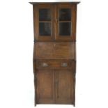 An oak Arts and Crafts bureau bookcase with shaped top over two glazed panel doors,