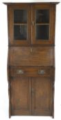 An oak Arts and Crafts bureau bookcase with shaped top over two glazed panel doors,