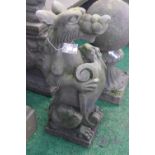 A pair of reconstituted stone sejant heraldic dogs, each holding a shield and snarling,