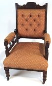A late Victorian mahogany arm chair with button back, on turned legs with ceramic casters,