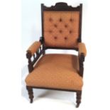 A late Victorian mahogany arm chair with button back, on turned legs with ceramic casters,