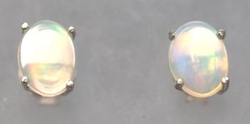 A white metal pair of single stone stud earrings. Each set with an oval cabochon cut welo opal.