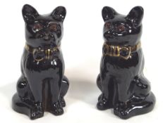 A pair of glazed terracotta figures of sejant cats, wearing bow ties,