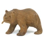 A Black Forest style carved figure of a walking bear carrying a salmon in its mouth,