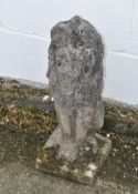 A reconstituted stone lion, sitting proud on a square base,