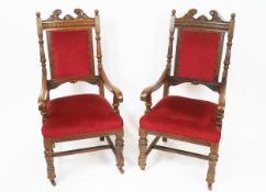 A pair of Victorian oak armchairs, with broken swan neck pediment, above a lozenge carved frieze,