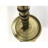A late 18th/early 19th century brass candlestick with flared drip pan