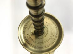 A late 18th/early 19th century brass candlestick with flared drip pan