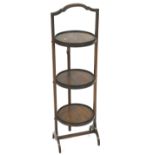 A mahogany three tier cake stand with shaped handle and folding action,