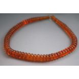 A single strand of graduated orange tablet beads. Strung plain and finished with a hook clasp.