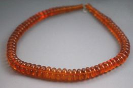 A single strand of graduated orange tablet beads. Strung plain and finished with a hook clasp.