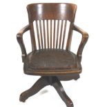An oak office leather chair, with arms, swivelling on four splayed legs each with casters,
