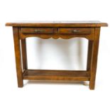 An oak console table with two frieze drawers, the square tapering legs linked by a shelf,