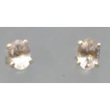 A pair of white metal single stone stud earrings. Each set with an oval faceted cut pale morganite.