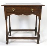 An oak joined side table with central drawer and brass drop handles, with shaped apron,