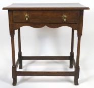 An oak joined side table with central drawer and brass drop handles, with shaped apron,