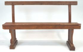 An early 20th century oak bench, having a top rail on curved supports, raised on block feet,