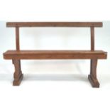 An early 20th century oak bench, having a top rail on curved supports, raised on block feet,