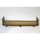 A brass fender, the pierced gallery with interlocking flower heads, on paw feet,