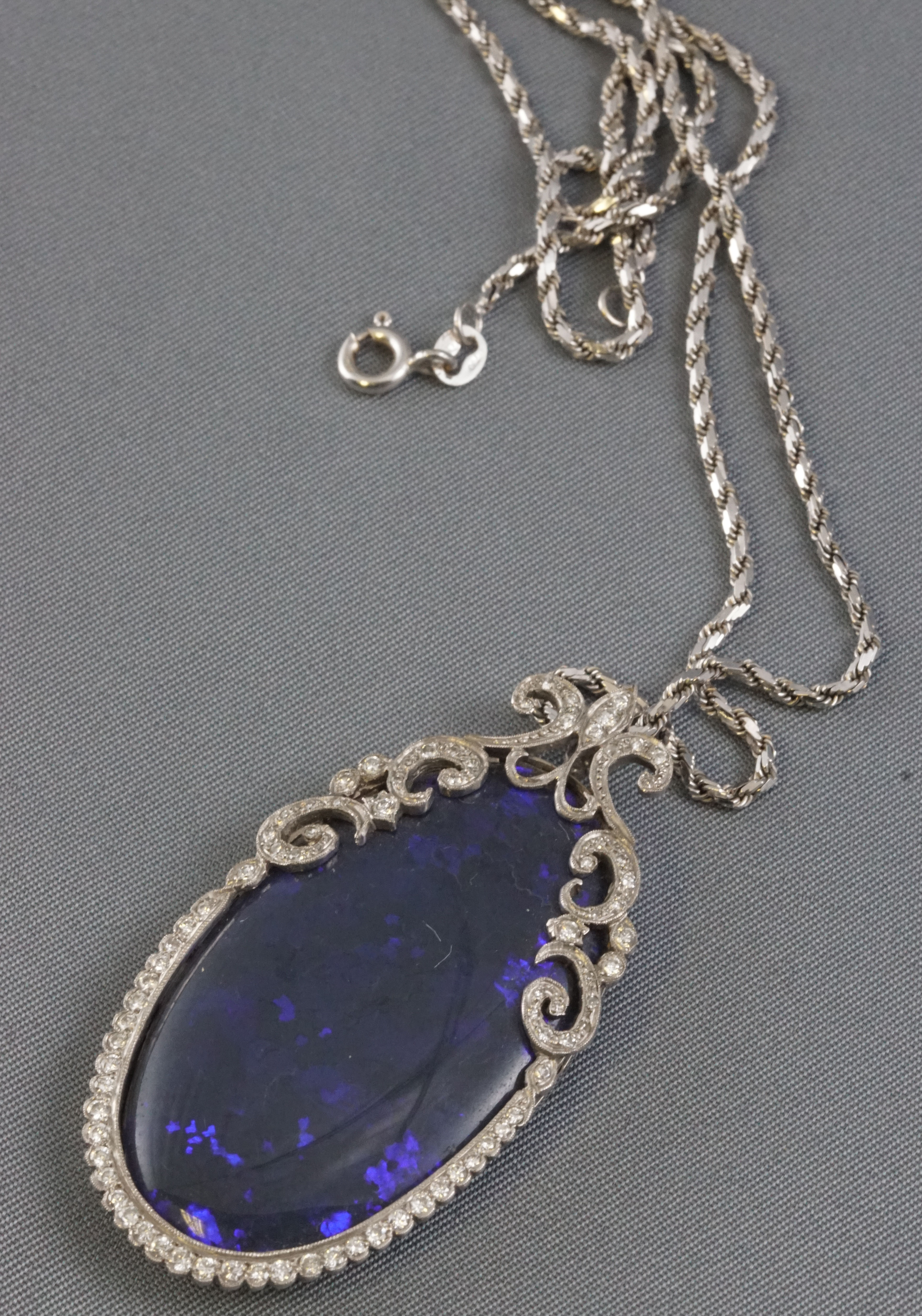 A white metal Edwardian style pendant principally set with an oval cabochon cut black opal