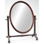 A Victorian mahogany swing frame mirror, of oval form with flared supports issuing scroll feet,