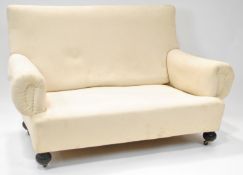 A calico upholstered sofa with two loose feather filled cushions on ebonised bun feet