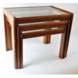 A 1960's retro vintage teak nest of tables, each having inset glass tops,