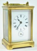 A brass carriage clock with alarm, with five glass panels and a white enamel Roman dial,
