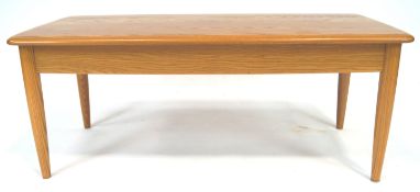 An Ercol elm wood coffee table with shaped rectangular top on plain legs,