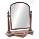 A Victorian mahogany swing mirror, of arched form, supported by fluted flared columns,