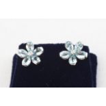 A white metal pair of floral stud earrings each set with five pear cut aquamarines