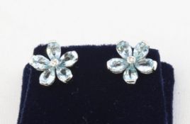 A white metal pair of floral stud earrings each set with five pear cut aquamarines