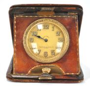 An early 20th century eight day travel clock in leather case, the dial inscribed Pearce & Sons Ltd,