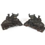 A pair of Chinese carved wood sculptures of water buffalo with a seated figure on their backs,