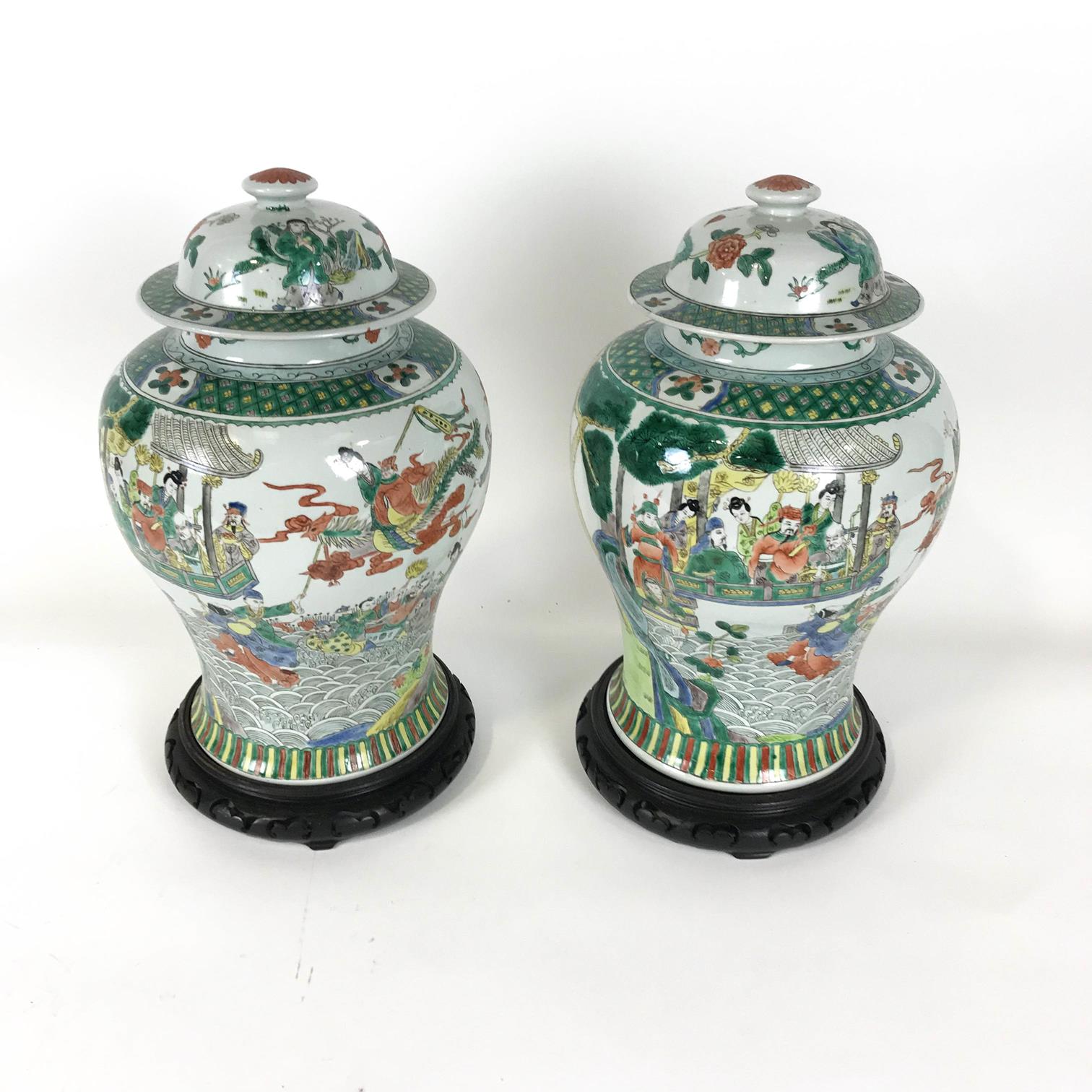 A pair of baluster Famille Verte vases (one cracked) and covers, painted with figures in pavilions,