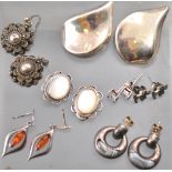 A collection of seven pairs of silver earrings of variable designs.