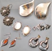 A collection of seven pairs of silver earrings of variable designs.