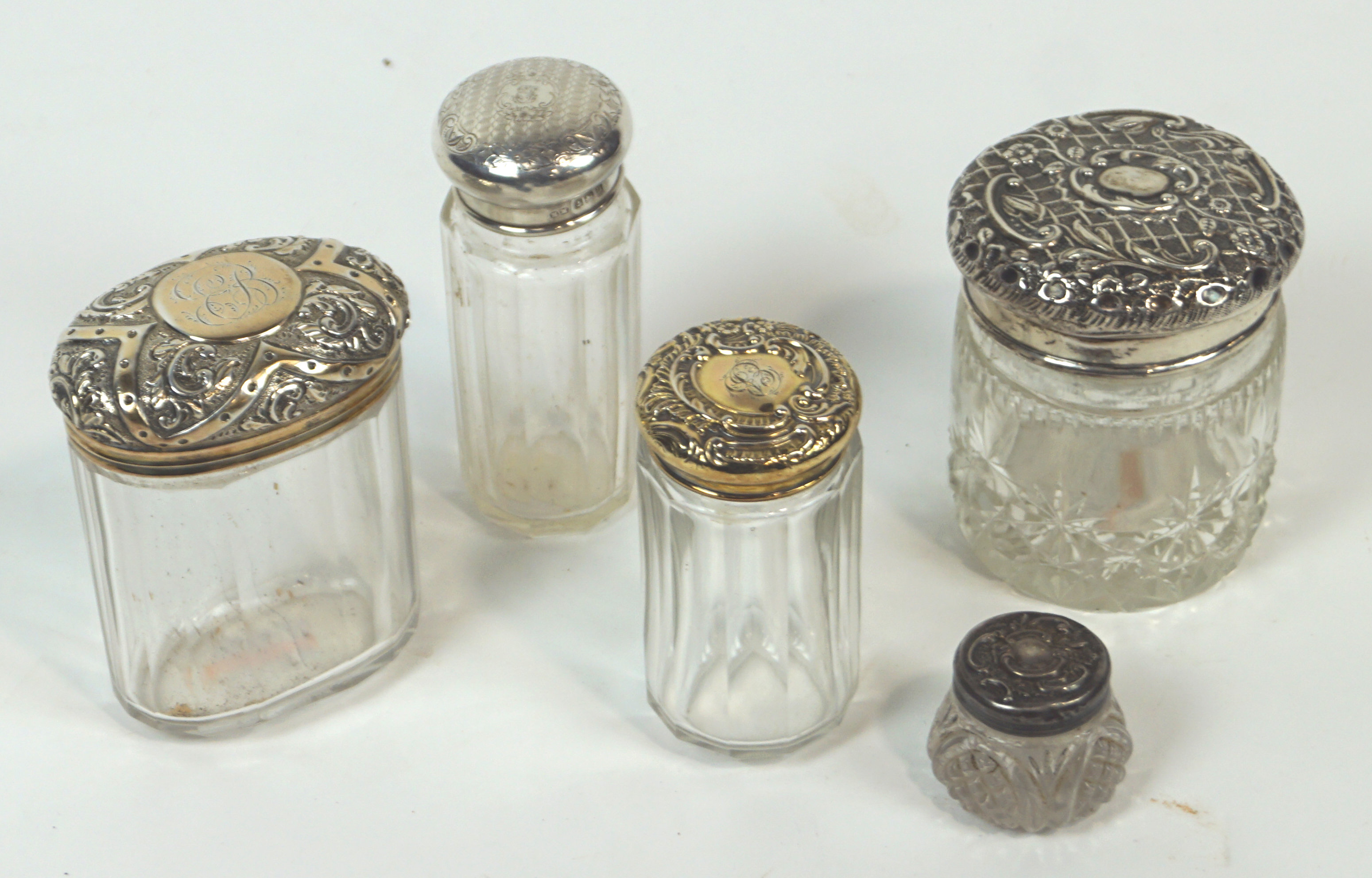 A group of five silver and white metal cut glass dressing jars, two gilt finish, two un-marked,