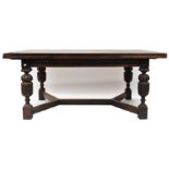 An oak extending dining table, of rectangular form, raised on acanthus carved cup and cover legs,