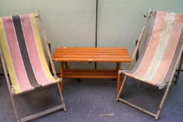 A wooden table and two deck chairs