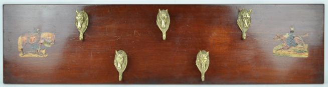 A coat rack with five bass horse head hooks, mounted on a mahogany board with decoupage prints,