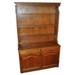 An oak dresser with three shelf top over a two door cupboard and two drawers,