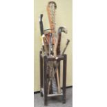 An oak stick stand containing assorted walking sticks