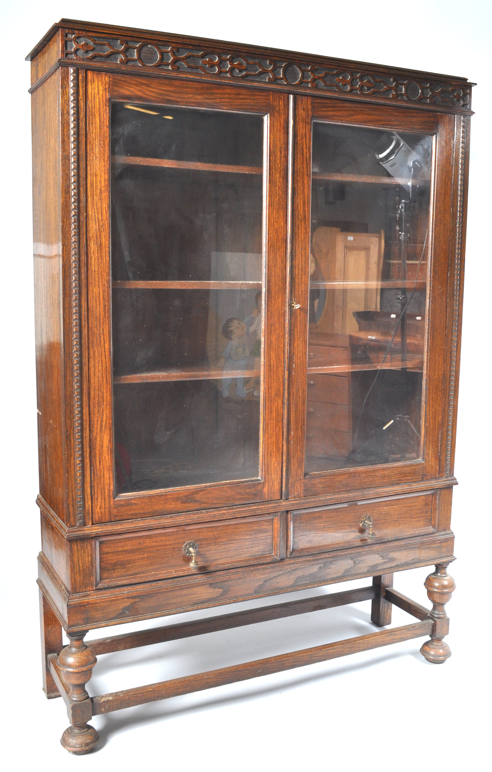 An oak display cabinet with two glazed doors above two frieze drawers on baluster turned legs, - Image 2 of 4