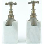 A pair of white marble book ends, surmounted by a brass hot and cold tap,