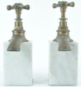 A pair of white marble book ends, surmounted by a brass hot and cold tap,