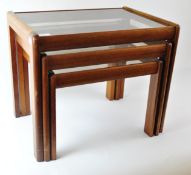 A 1960's retro vintage teak nest of tables, each having inset glass tops,