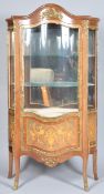 A French style serpentine fronted glazed vitrine display cabinet having gilt ormolu decoration and